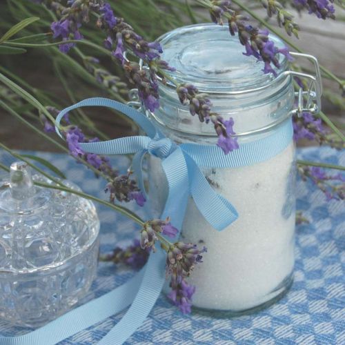 Einmachglas gefüllt mit Lavendelzucker, dekoriert mit blauer Schleife und Lavendelblüten