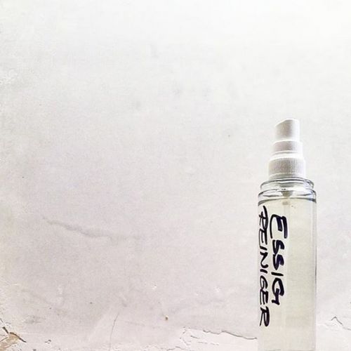 Essigreiniger in Glas-Sprayflasche vor weißem Hintergrund