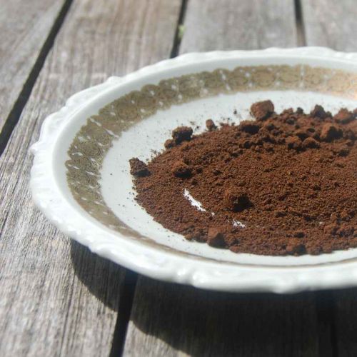 Getrockneter Kaffeesatz auf einem kleinen Teller mit Goldrand.