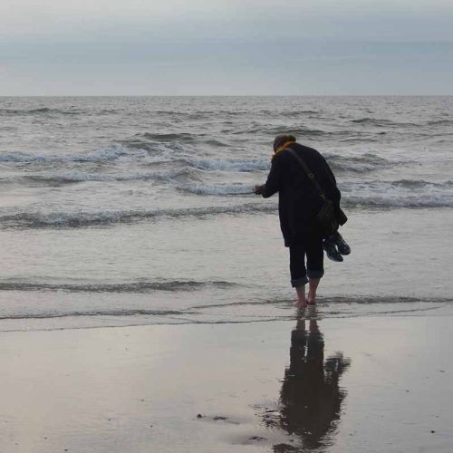 Silhouette Frau am Strand, vor grauem Meer