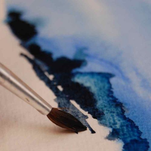 Pinsel auf Aquarellpapier - eine kleine Aquarell-Landschaft in blau entsteht