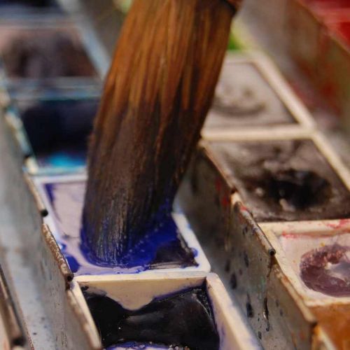 Aquarell-Pinsel taucht in flüssige Aquarellfarbe in dunklem Blau