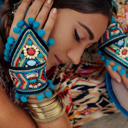 Frau mit buntem Ethno-Schmuck - Halsreifen, Armreifen und blauen Bommeln