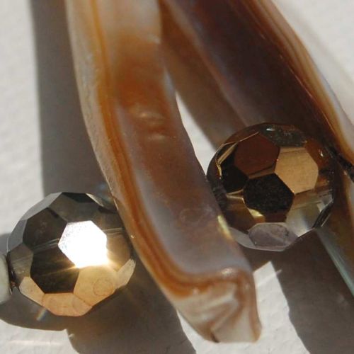 Großaufnahme goldschimmernde facettierte Glasperlen mit Perlmuttstäben