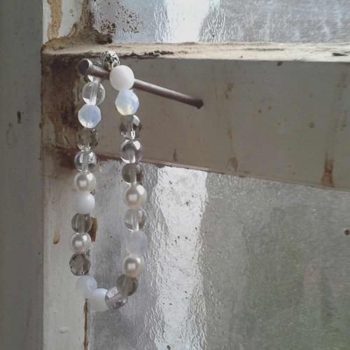 Glasperlen-Armband in Naturtönen an Nagel vor altem Fenster